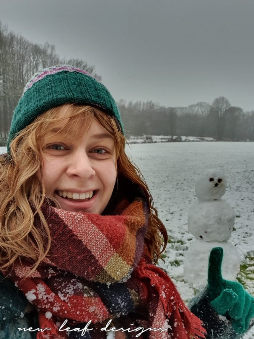 Carmen laughing at the camera and pointing at snowman behind her